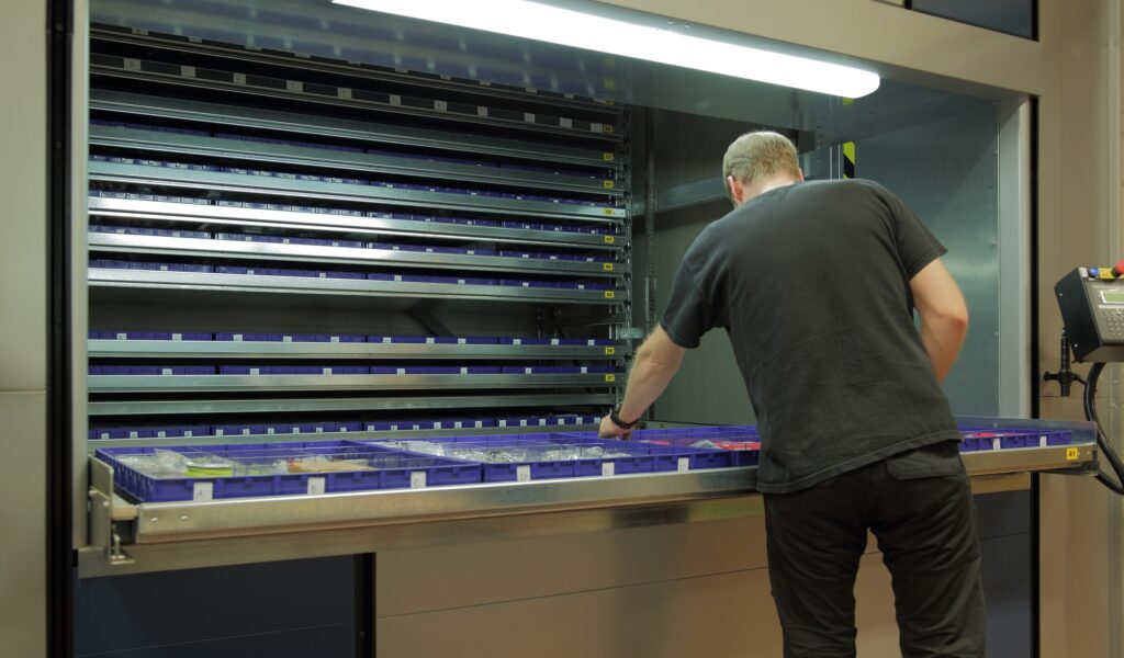 A man filling a vertical carousel in a warehouse